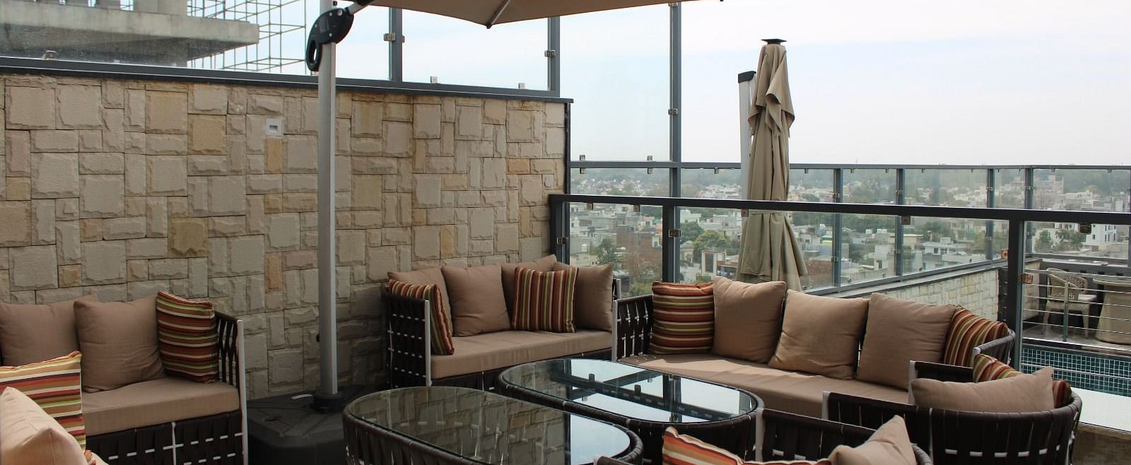 Rooftop lounge featuring sofas, pillows, and a patio offering stunning city views at BluSalzz Residence, Amritsar